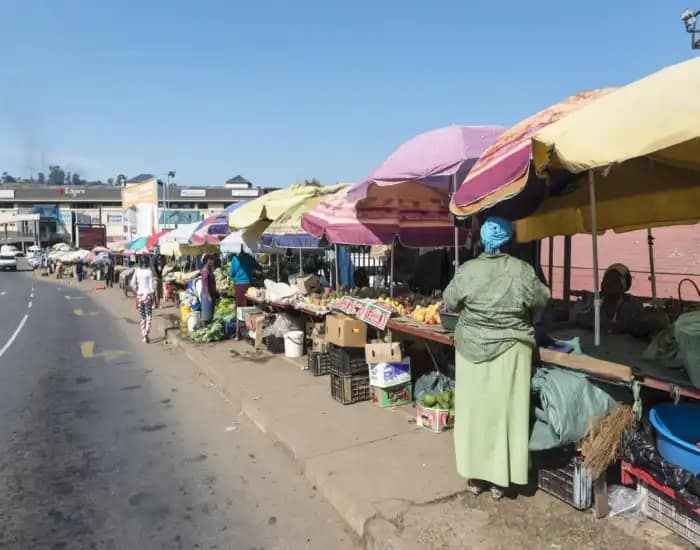 Explore Eswatini: 12 Astonishing Facts About Africa's Hidden Kingdom - Travel Guide 7 Outdoor market stalls lined with colorful umbrellas selling fruits and vegetables.